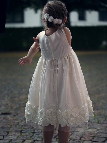 Blumenkind auf der Hochzeit vor der Kirche in Kleid