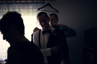 Bruder hilft Bräutigam bei Anzug anziehen